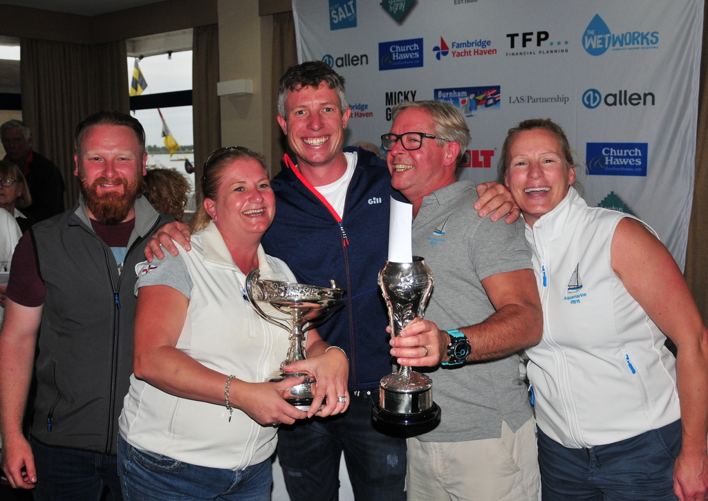 Stuart Bithell – Olympic gold medallist – presents Team Aquamarine – Angela Shephard (left), Matt Shephard and Sarah Hastwell – with the winners’ trophies in the Royal Burnham One-Design class – photo Alan Hanna